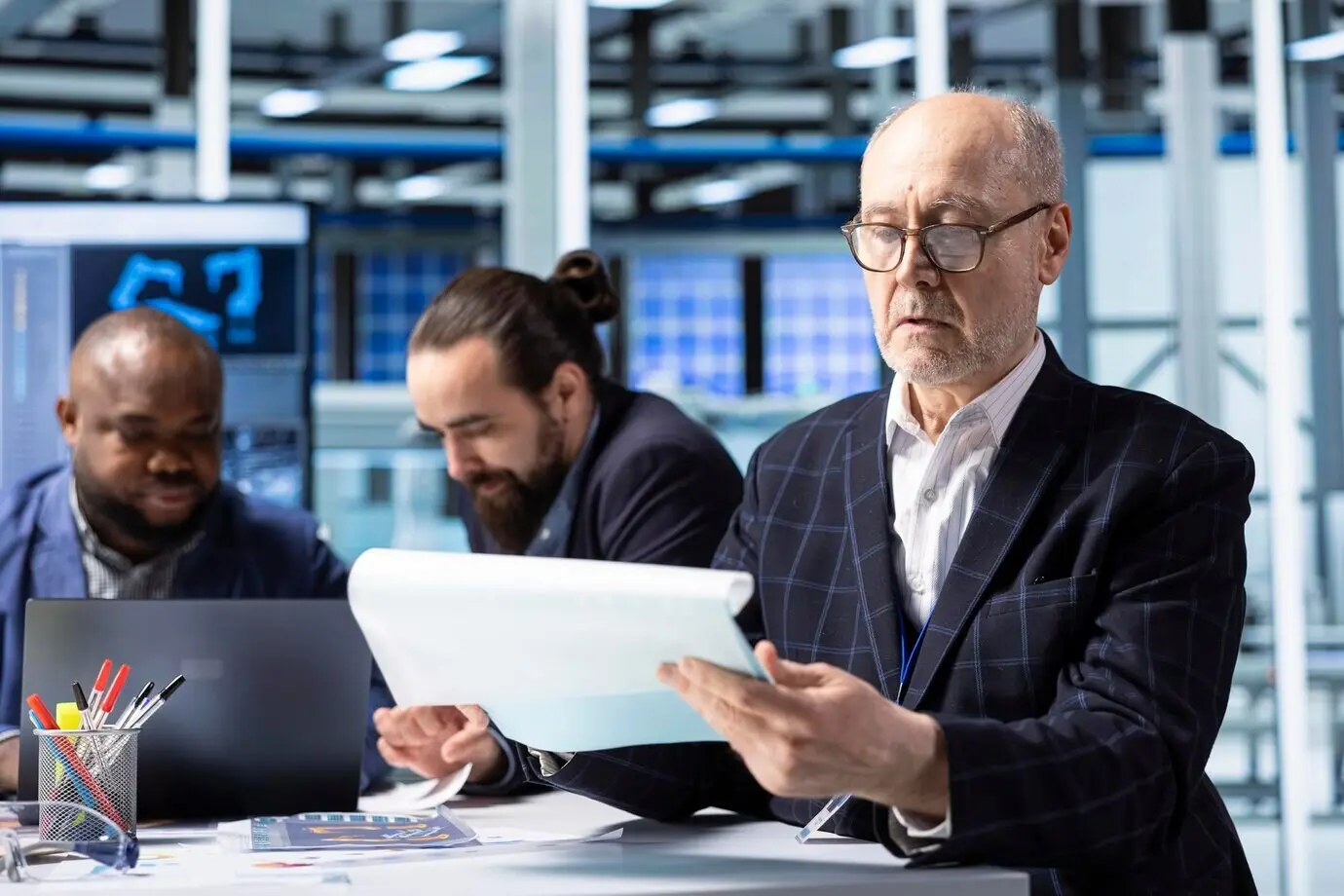 Älterer Anteilseigner einer Industrieanlage betrachtet Unterlagen zur Analyse des Umsatzes.